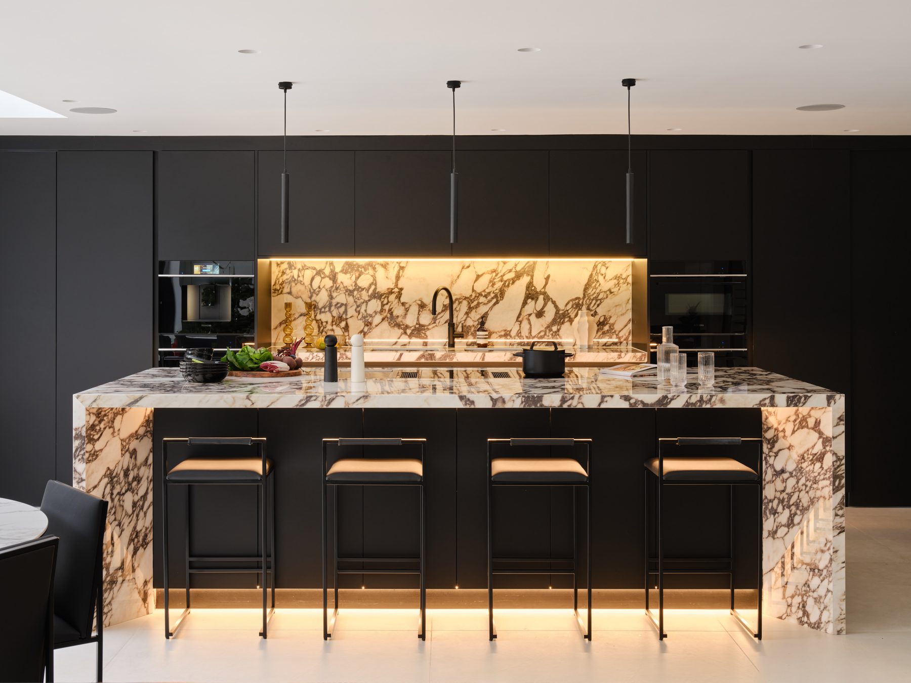 A finished Sheraton kitchen in black with a backlit veined island and matching splashback